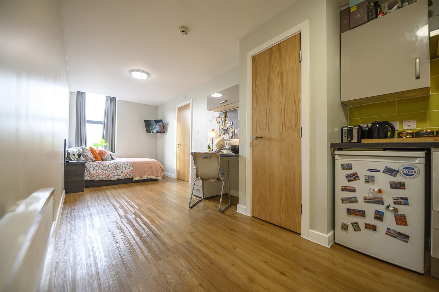 full view of a large student studio apartment with bed, bathroom and kitchen
